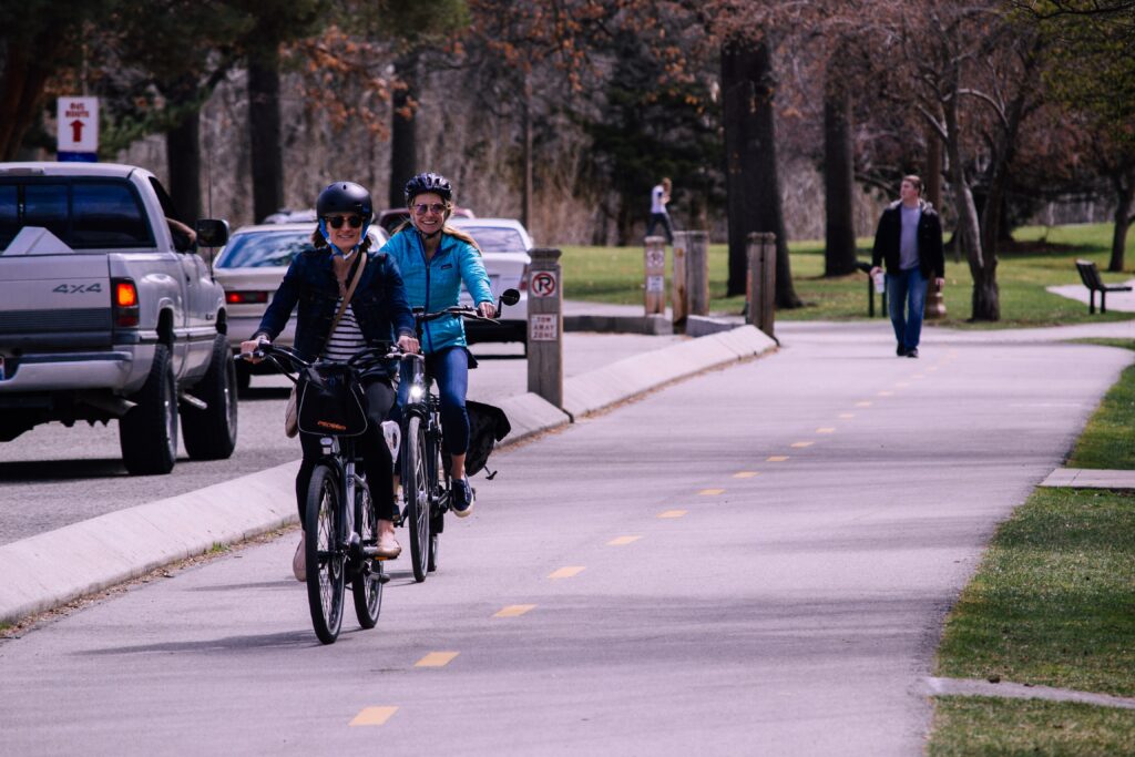 Photograph showing two people cycling on a protected bike lane that runs along a road.