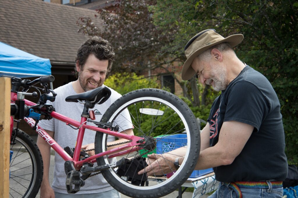 photo of two men at the Repair Cafe 2024 who are working on a red bicycle.